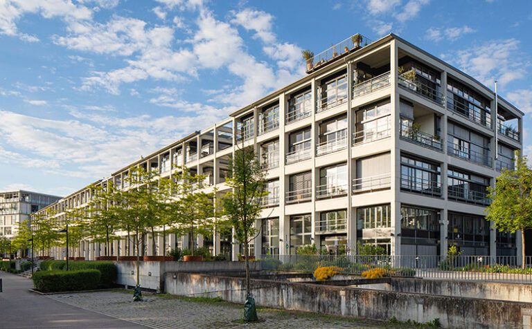 Stadtregal Ulm, modernes Büro- und Dienstleistungsgebäude mit Parkplätzen und kleinen Bäumen, blauer Himmel mit Wolken