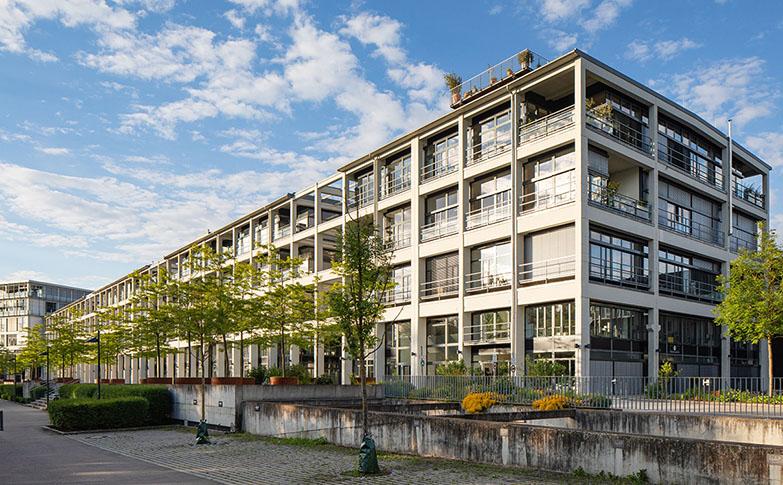 Stadtregal Ulm, modernes Büro- und Dienstleistungsgebäude mit Parkplätzen und kleinen Bäumen, blauer Himmel mit Wolken