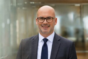 Portrait eines Mitarbeiters von fgi im Anzug in einer modernen Büroumgebung.